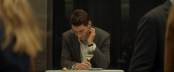 Movie still from “Black Box” (2021), directed by Yann Gozlan – A man sitting at a table with a glass of white wine; Close Up shot, Low angle