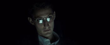 Movie still from “Black Box” (2021), directed by Yann Gozlan – A man wearing glasses looking at the camera; Close Up shot, Low angle