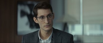Movie still from “Black Box” (2021), directed by Yann Gozlan – A person wearing glasses and a suit; Close Up shot, Over the shoulder angle