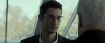 Movie still from “Black Box” (2021), directed by Yann Gozlan – A person wearing a suit and glasses; Close Up shot, Over the shoulder angle
