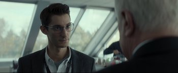 Movie still from “Black Box” (2021), directed by Yann Gozlan – A man wearing glasses and a suit is talking to another man; Close Up shot, Over the shoulder angle