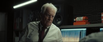 Movie still from “Black Box” (2021), directed by Yann Gozlan – An older man in a white shirt and red tie; Close Up shot, Over the shoulder angle