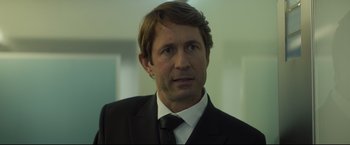 Movie still from “Black Box” (2021), directed by Yann Gozlan – A person wearing a suit and tie; Close Up shot, Over the shoulder angle