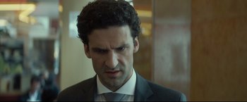 Movie still from “Black Box” (2021), directed by Yann Gozlan – A person wearing a suit and tie; Close Up shot, Over the shoulder angle