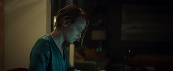 Movie still from “Black Box” (2021), directed by Yann Gozlan – A woman sitting at a table in a dark room; Close Up shot, Over the shoulder angle