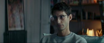 Movie still from “Black Box” (2021), directed by Yann Gozlan – A man with glasses is sitting in a room; Close Up shot, Over the shoulder angle