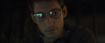 Movie still from “Black Box” (2021), directed by Yann Gozlan – A person wearing glasses and headphones; Close Up shot, Low angle