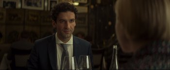 Movie still from “Black Box” (2021), directed by Yann Gozlan – A man sitting at a table with a glass of wine in front of him; Close Up shot, Over the shoulder angle