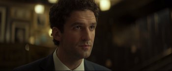 Movie still from “Black Box” (2021), directed by Yann Gozlan – A person wearing a suit and tie; Close Up shot, Over the shoulder angle