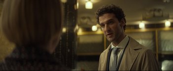 Movie still from “Black Box” (2021), directed by Yann Gozlan – A man wearing a suit and tie talking to a woman in front of a mirror; Close Up shot, Over the shoulder angle