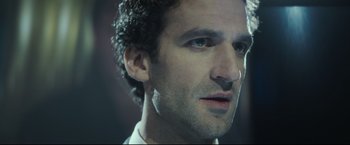 Movie still from “Black Box” (2021), directed by Yann Gozlan – A man's face in a dark room; Close Up shot, Low angle