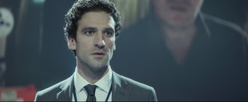 Movie still from “Black Box” (2021), directed by Yann Gozlan – A person wearing a suit and tie; Close Up shot, Over the shoulder angle