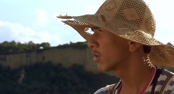 Movie still from “Black Cat, White Cat” (1998), directed by Emir Kusturica – A man wearing a straw hat looking into the distance; Close Up shot, Low angle