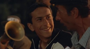 Movie still from “Black Cat, White Cat” (1998), directed by Emir Kusturica – A person smiling with another person; Close Up shot, Over the shoulder angle