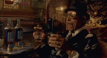 Movie still from “Black Cat, White Cat” (1998), directed by Emir Kusturica – An old man holding a glass of whiskey and a cell phone; Close Up shot, Low angle