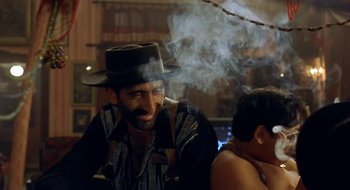 Movie still from “Black Cat, White Cat” (1998), directed by Emir Kusturica – A man smoking a pipe while sitting next to another man; Close Up shot, Low angle