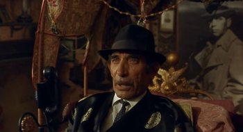 Movie still from “Black Cat, White Cat” (1998), directed by Emir Kusturica – An older man wearing a black hat and a suit; Close Up shot, High angle