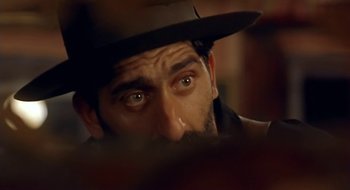Movie still from “Black Cat, White Cat” (1998), directed by Emir Kusturica – A person wearing a hat; Extreme Close Up shot, Over the shoulder angle