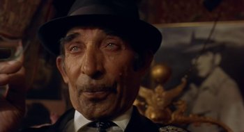 Movie still from “Black Cat, White Cat” (1998), directed by Emir Kusturica – An older man wearing a hat and a tie; Close Up shot, Low angle