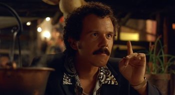 Movie still from “Black Cat, White Cat” (1998), directed by Emir Kusturica – A man with curly brown hair and a mustache; Close Up shot, Low angle