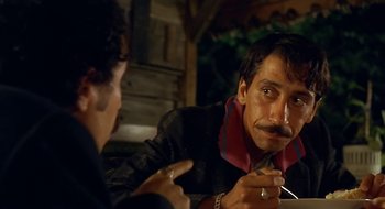 Movie still from “Black Cat, White Cat” (1998), directed by Emir Kusturica – Two men sitting at a table talking to each other; Close Up shot, Over the shoulder angle