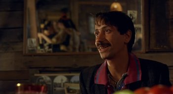 Movie still from “Black Cat, White Cat” (1998), directed by Emir Kusturica – A man with a mustache is smiling at the camera; Close Up shot, Low angle