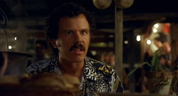 Movie still from “Black Cat, White Cat” (1998), directed by Emir Kusturica – A man in a hawaiian shirt is eating a sandwich; Close Up shot, Over the shoulder angle