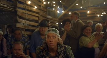 Movie still from “Black Cat, White Cat” (1998), directed by Emir Kusturica – A group of people standing around a room with lights; Medium shot, Low angle