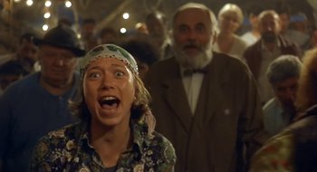 Movie still from “Black Cat, White Cat” (1998), directed by Emir Kusturica – A young girl with an open mouth standing next to an older man; Close Up shot, Low angle