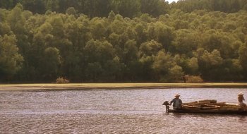 Movie still from “Black Cat, White Cat” (1998), directed by Emir Kusturica – A person in a boat on a river; Extreme Wide shot, High angle