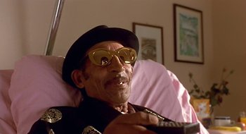 Movie still from “Black Cat, White Cat” (1998), directed by Emir Kusturica – An older man wearing sunglasses and a hat; Close Up shot, Low angle