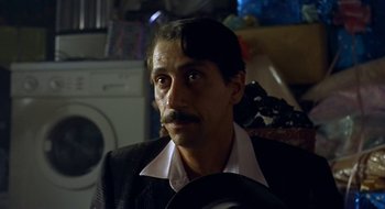 Movie still from “Black Cat, White Cat” (1998), directed by Emir Kusturica – A person wearing a suit and tie; Close Up shot, Low angle