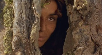 Movie still from “Black Cat, White Cat” (1998), directed by Emir Kusturica – A woman peeking through a hole in a tree; Close Up shot, High angle
