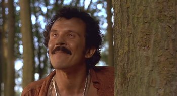 Movie still from “Black Cat, White Cat” (1998), directed by Emir Kusturica – A person near a tree; Close Up shot, Low angle