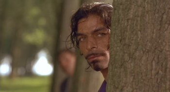 Movie still from “Black Cat, White Cat” (1998), directed by Emir Kusturica – A person leaning against a tree; Close Up shot, Low angle