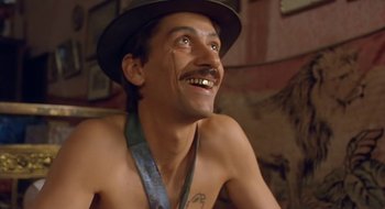 Movie still from “Black Cat, White Cat” (1998), directed by Emir Kusturica – A man with a mustache and a hat is smiling for the camera; Close Up shot, Low angle