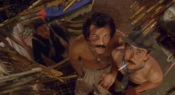 Movie still from “Black Cat, White Cat” (1998), directed by Emir Kusturica – A man with a mustache and a hat is standing next to another man with a mustache; Close Up shot, Overhead angle