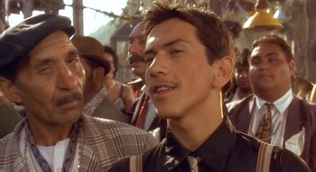 Movie still from “Black Cat, White Cat” (1998), directed by Emir Kusturica – A person wearing a shirt and a tie; Close Up shot, Low angle