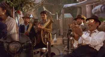 Movie still from “Black Cat, White Cat” (1998), directed by Emir Kusturica – A group of men playing musical instruments in a field; Medium shot, Over the shoulder angle