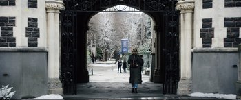 Movie still from “Black Christmas” (2019), directed by Sophia Takal – A woman is walking through an archway of a building; Extreme Wide shot, High angle