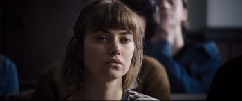 Movie still from “Black Christmas” (2019), directed by Sophia Takal – A person with a crowd in the background; Close Up shot, Over the shoulder angle