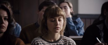 Movie still from “Black Christmas” (2019), directed by Sophia Takal – A woman with her eyes closed sitting in front of two other people; Close Up shot, Over the shoulder angle