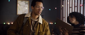 Movie still from “Black Christmas” (2019), directed by Sophia Takal – A man in a brown jacket wearing glasses and a yellow jacket; Close Up shot, Over the shoulder angle