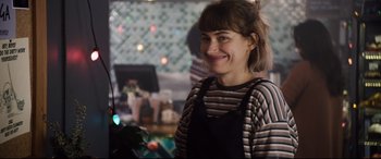Movie still from “Black Christmas” (2019), directed by Sophia Takal – A woman smiling for the camera in front of a christmas tree; Close Up shot, Over the shoulder angle