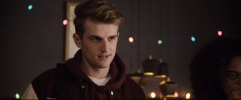 Movie still from “Black Christmas” (2019), directed by Sophia Takal – A young man in a maroon jacket is looking at the camera; Close Up shot, Over the shoulder angle