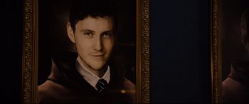 Movie still from “Black Christmas” (2019), directed by Sophia Takal – A man in a suit and tie in front of a picture; Close Up shot, Low angle