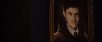 Movie still from “Black Christmas” (2019), directed by Sophia Takal – A portrait of a young man in front of an ornate gold frame; Close Up shot, Over the shoulder angle