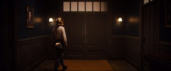 Movie still from “Black Christmas” (2019), directed by Sophia Takal – A woman walking in front of a garage door; Wide shot, Low angle