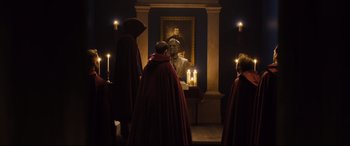 Movie still from “Black Christmas” (2019), directed by Sophia Takal – A group of people standing in front of a painting; Wide shot, Over the shoulder angle