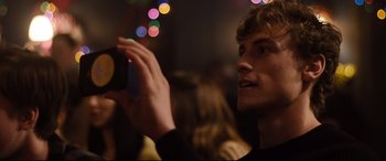 Movie still from “Black Christmas” (2019), directed by Sophia Takal – A man holding up a cell phone to take a picture; Close Up shot, Over the shoulder angle